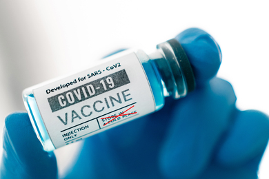 A gloved hand holds bottle of vaccine dosage 