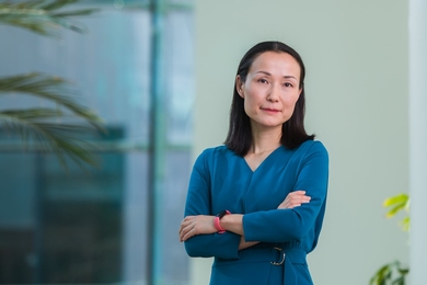 Portrait of Haruko Wainwright standing indoors with a glass wall to the left