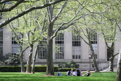 8 people sit together on an MIT couryard in spring
