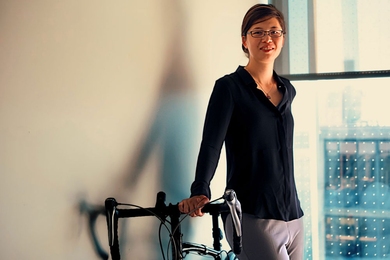 Photo of Cathy Wu, leaning against a wall with a bicycle