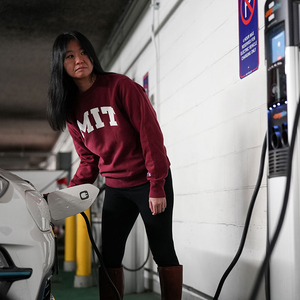 Women in MIT sweatshirt charging her electric vehicle on campus