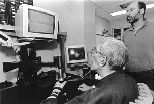 MIT Research Scientist Hermano I. Krebs watches as a patient at the Burke Rehabilitation Hospital uses MIT-Manus, a robotic arm designed to aid in his recovery.