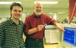 Professor Richard O. Hynes, director of the Center for Cancer Research, holds a glass slide containing thousands of bits of DNA that have been exposed to genetic material from tumor cells. He and former postdoctoral fellow Edwin A. Clark (left), now at Millennium Predictive Medicine in Cambridge, collaborated with other scientists to identify the gene responsible for cancer metastasis.