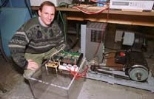 Research scientist David Perreault kneels next to an alternator that could dramatically increase the power available to future cars. The laboratory-scale apparatus nearest Dr. Perreault contains the new switches that enable this increase; the other part of the alternator is at right.