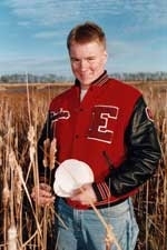 Jordan Sand, winner of the Lemelson high school apprenticeship award, stands among cattails, holding an alternative form of paper he made from corn, flax, wheat and cattails.