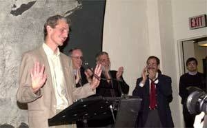 Professor Wolfgang Ketterle unsuccessfully tries to still the applause that greeted him at the MIT news conference about his Nobel Prize. Behind him are (left to right) President Charles M. Vest, Dean of Science Robert Silbey and Professor Marc Kastner, head of the physics department.
