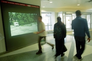 Passersby catch a few frames of Euan Macdonald's short film "Three        Trucks" showing on the "Media Test Wall" in the Building 56 corridor.