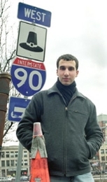Yanni Tsipis stands next to the Massachusetts  turnpike sign at the Massachusetts Avenue ramp.