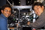 The experimental apparatus which produced the continuous BEC source is shown with two of the graduate students on the experiment.  Ananth Chikkatur, left, points to the science chamber, in which the source was made.  Yong-Il Shin points to the production chamber where the BEC'swere produced, and then transferred to the science chamber (32 cm away) using optical tweezers.