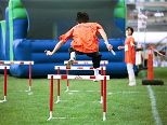 A member of the Magic Dragons carries the baton over the hurdles to his waiting teammate.