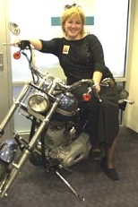 Kimberly Shooter, chief marketing officer of the MIT Credit Union, leans against a Harley that will be featured at MIT's annual Transportation Fair and raffled off as part of a fund-raiser.