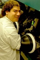 Seth Coe,  a graduate student in electrical engineering and computer science, inspects a  vial of fluorescing quantum dots in preparation for fabricating a QD-OLED.