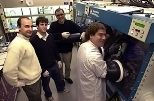 Vladimir Bulovic, assistant professor in electrical engineering and computer science, chemistry graduate student Jonathan Steckel and chemistry professor Moungi Bawendi (from left), watch as Seth Coe, a graduate student in electrical engineering and computer science, inspects a vial of fluorescing quantum dots in preparation for fabricating a light-emitting device.