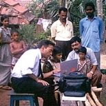 MIT professor Pawan Sinha, seated at left, works in a village with a little girl who gained sight after being blind for the first seven years of her life.