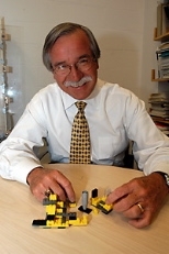 Professor Andrew Kadak builds a "power plant" of Legos to demonstrate the modular approach to constructing a pebble-bed nuclear plant. Each Lego brick represents a module containing specified plant components. The modules can be made in factories with high quality control, transported to a site, and assembled Lego-like into a power plant.
