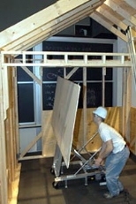Dale Cotton, a junior in mechanical engineering, demonstrates the drywall/sheetrock lift and installation system designed and built by his team in 2.009 (Product Engineering Processes).