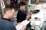 Cosmonaut Gennady I. Padalka, Expedition 9 commander, works with the torso portion of an Extravehicular Mobility Unit space suit during a training session in the International Space Station (ISS) Quest airlock mockup/trainer in the Space Vehicle Mockup Facility at the Johnson Space Center. Astronaut Edward Michael (Mike) Fincke, NASA ISS science officer and flight engineer, looks over a procedures...