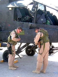 Prior to evening patrol in Iraq, AH-64 Apache pilots don survival gear after being instrumented.