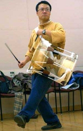 Sung-Hee Do plays a traditional Korean instrument called a "Jang-go" at Oori practice.