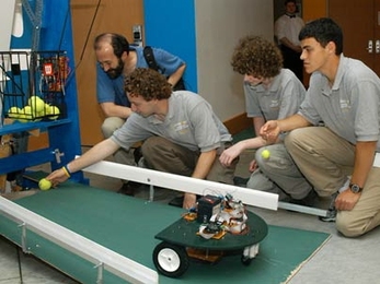 Vermont's Essex High School team demonstrates its robotic tennis ball retriever, Roboscooper, one of the inventions presented at the InvenTeams Odyssey held at MIT. Ben Rome places a ball prior to the demonstration while Alex Franz looks on at right.