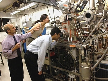 Senior research scientist Jagadeesh Moodera, left, points to the molecular beam epitaxy setup he uses in his research. With him are Tiffany Santos, graduate student in materials science and engineering, and postdoctoral associate John Philip.