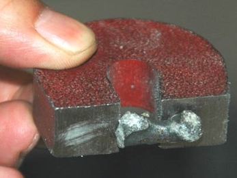 A droplet of iron held by a magnet. The iron was produced by an MIT team using molten oxide electrolysis, which generates no carbon dioxide gases -- only oxygen.