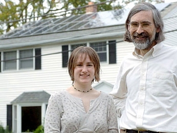 Professor David Vogan poses with his daughter, Ali, in front of their home in Arlington. The solar panels on their roof were installed thanks to support from MIT.