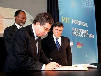 Jose Mariano Gago, the Portuguese minister of science, technology and higher education, at left, signs a document signalling a collaboration between MIT and many of Portugal's top national universities. At rear, MIT Chancellor Phillip Clay and JoÃ£o Sentieiro, chairman of the board of the MIT-Portugal Program, look on.