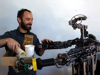 MIT postdoctoral associate Aaron Edsinger gets some help from Domo, an assistive robot he has been developing for the last three years.