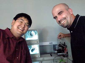 Paul Huang, graduate student in biological engineering, left, and Professor Forest White of biological engineering with a mass spectrometer showing the electrospray ionization tip of a liquid chromatography column.  Samples are loaded on the column and electrosprayed into the mass spectrometer, where their mass and sequence is identified, allowing White and Huang to analyze the sample.