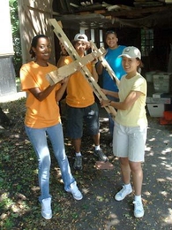 Carrying a frame are MIT freshmen Eden Zeilo from Virginia, left, Josh Raines from New Jersey and Jessica Li of California. Behind them is sophomore Arian Roman, the team leader of a CityDays group volunteering on a project for the Cambridge Historical Society.