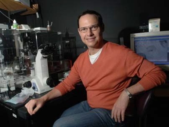 Biology professor Frank Gertler sits by a microscope in his lab. Gertler leads a team that's uncovered new insights on early development of the nervous system.