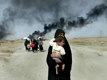 An Iraqi woman carries her young child as she flees with others from the southern Iraqi town of Basra in March 2003. This and accompanying photos are featured on the new MIT web site, Iraq: The Human Cost.