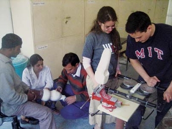 MIT students Maria Luckyanova and Philip Garcia (at right) operate their prosthetic-fitting device at the Jaipur Foot Organization headquarters in India in January, as JFO specialists work on fitting a prosthetic leg on a patient.