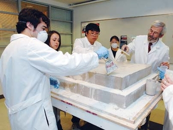 From left, MIT freshman Daniel Sauza, sophomore Stephanie Brown and seniors Ceryen Tan and Joyce Chen (in mask) work with materials science and nuclear engineering professor Linn Hobbs to cover limestone blocks with mortar as they build up their pyramid on the sixth floor of Building 16.