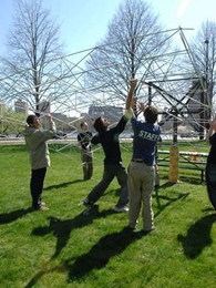 MIT students work on a new kind of solar generator that employs low-cost materials. Here they mount the frame of the concentrator (which will be mounted with mirrors) on the base near Tang Hall on Memorial Drive.