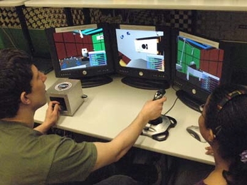An aeronautics and astronautics project led by MIT researcher Chuck Oman aims to provide better training systems for astronauts to learn how to use robotic arms in space. At left, Joseph Silverman, a sophomore in mechanical engineering, tries his hand with the joysticks that control the robotic arm. At right is graduate student Zakiya Tomlinson, who is running the experiment.