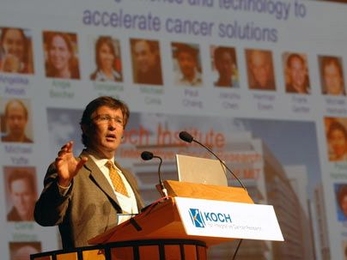 Tyler Jacks, Director of the David H. Koch Institute for Integrative Cancer Research, gave the introduction at the 2008 Koch Institute Symposium entitled Nanotechnology and Cancer: The Power of Small Science, held at Kresge Auditorium on Friday, June 24. Behind him are pixtures of faculty members who comprise the Koch Institute. <a onclick="MM_openBrWindow('cancersym1-enlarged.html','','width=509,...