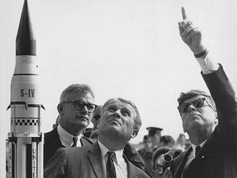 Then-NASA Deputy Administrator Robert Seamans, a former dean of the School of Engineering at MIT, stands behind Dr. Wernher von Braun as he explains the Saturn Launch System to President John F. Kennedy.