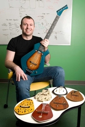 Media Lab student Amit Zoran shows the Chameleon Guitar, along with a variety of the interchangeable soundboards -- made of different woods and other materials -- that can be inserted to alter the guitar's acoustic characteristics.