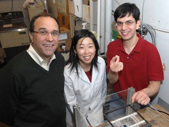 Recent PhD recipient Christophoros Vassiliou, right, holds the cancer monitoring device that he and Professor Michael Cima, left, and recent PhD recipient Grace Kim developed.