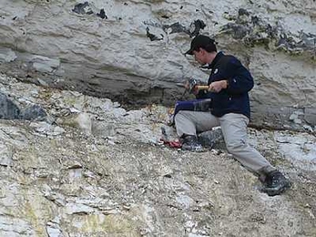 One of the paper's co-authors, Jens Wendler, chips away at a gray band in the cliffs at the Cretaceous-Paleogene Boundary (Fiskeler) at Kulstirenden, Stevns Klint, Denmark. This band represents the period of the mass extinction 65 million years ago and immediately afterwards, and is one of the thickest deposits in the world from that period.