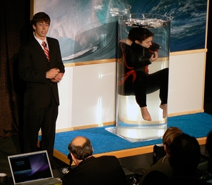 Taylor Williamson floats in a tank of water to demonstrate emergency breathing device, while her teammate Chris Peters explains the invention, at the final presentations for class 2.009.