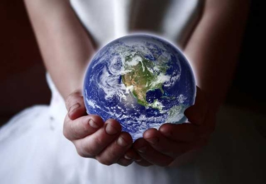 A person holds a glowing Earth in their hands. Their head and legs are not visible.