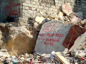 On rubble from the aftermath of the Haiti earthquake, a merchant has inscribed "Notice: The artist is not dead. Call 3907-9920 for your shirt-printing jobs."