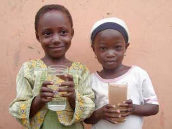 Two children in Ghana show the differences between water that has been cleaned with the Kosim filter, left, and water that has not.