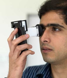 Postdoctoral Associate Ankit Mohan demonstrates NETRA (Near-Eye Tool for Refractive Assessment). The user places the device to the eye and, using phone's keypad, aligns patterns in the viewfinder. These alignments provide the data needed to determine a prescription.
