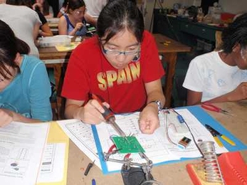 Students solder LEDs to a circuit board.