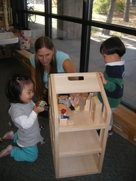 Karen Mikita, lead teacher at TCC Westgate, works with two preschool students engaged in dramatic play.