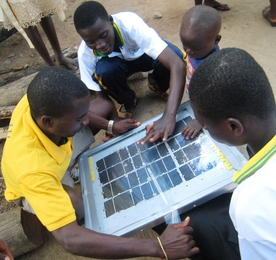 Three students from the Ghana Fab Lab put the finishing touches on a solar panel unit in Kobina Adorh Krom village, with help from a young friend.